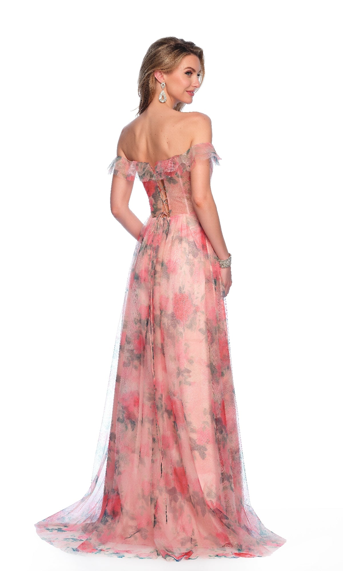 A woman models the Dave & Johnny 12076 Floral Print Prom Dress—an off-the-shoulder, floor-length gown in pink floral print—posing and glancing over her shoulder against a white background.
